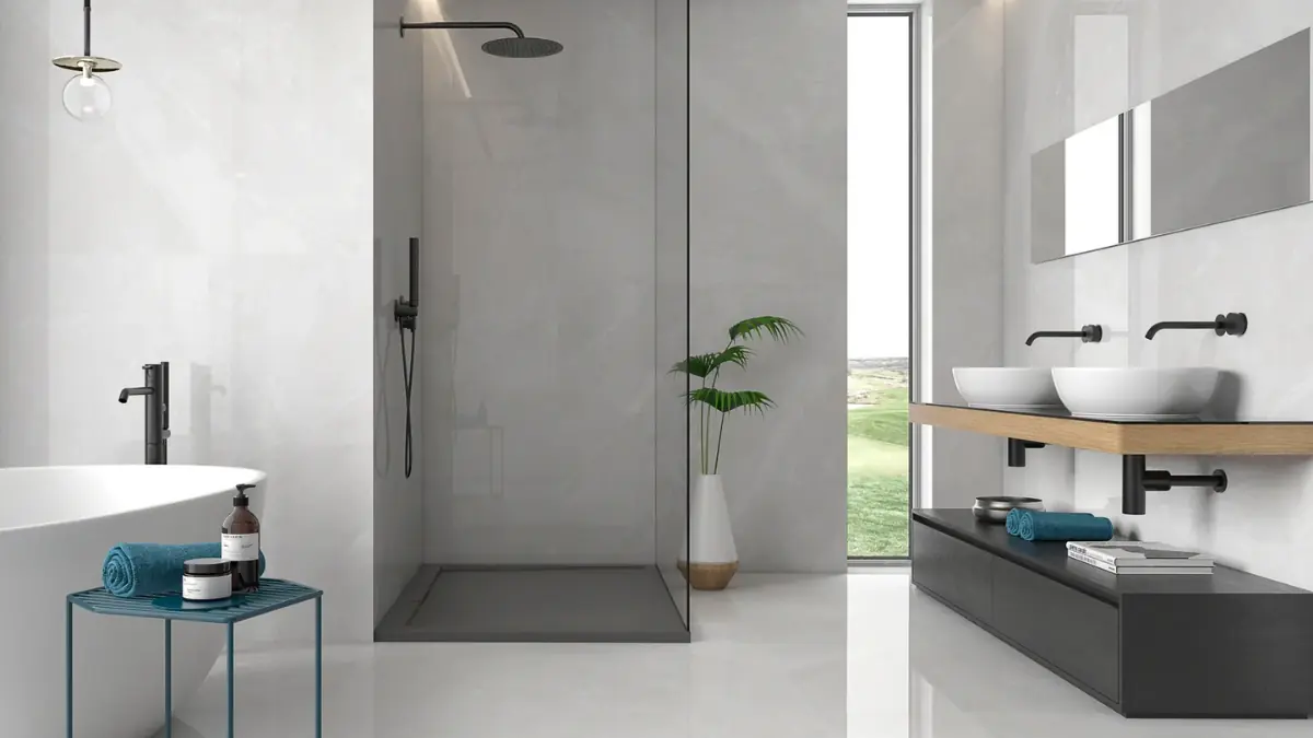 Elegant bathroom tiled in 600x600 Calacatta marble-effect porcelain — polished finish on walls and matt textured finish on the floor — with brushed black color taps and a freestanding bath