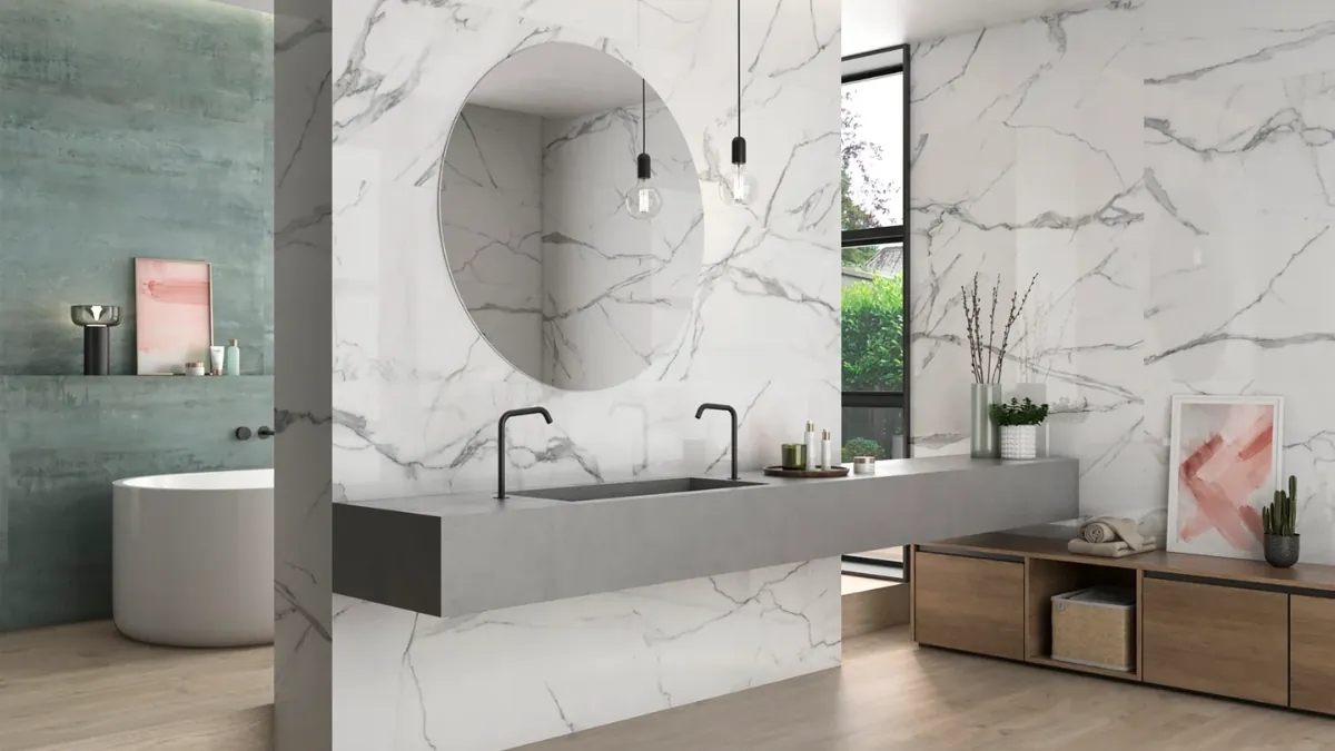 Luxury bathroom pairing a polished marble-effect feature wall behind the bath with a matt honed wall tile